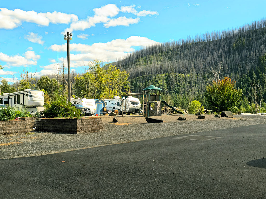 On-site playground and RV sites with forested hillside beyond